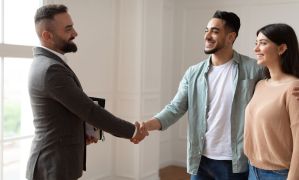 realtor shaking hand with clients after successful radon mitigation at closing